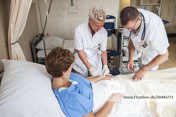 MODELL FREIGEGEBEN. Krankenschwester bereitet einen Patienten für einen IV-Anschluss vor Krankenschwester bereitet einen Patienten für einen IV-Anschluss vor