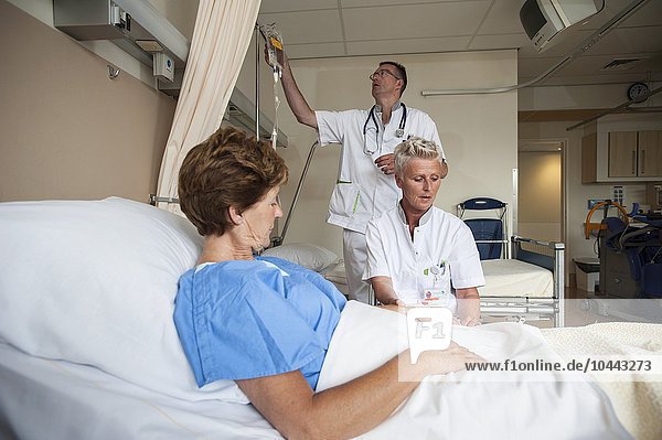 MODELL FREIGEGEBEN. Krankenschwestern bereiten einen Patienten für einen IV-Anschluss vor Krankenschwestern bereiten einen Patienten für einen IV-Anschluss vor