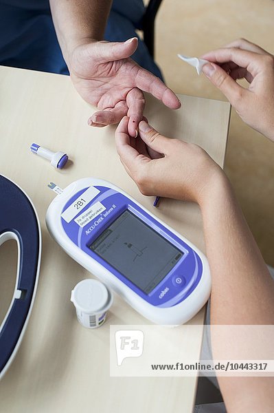 MODEL RELEASED. Blood glucose test. Nurse measuring a patient's blood glucose levels. Blood glucose test