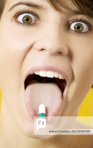 junge Frau hält eine Kapsel auf der Zunge