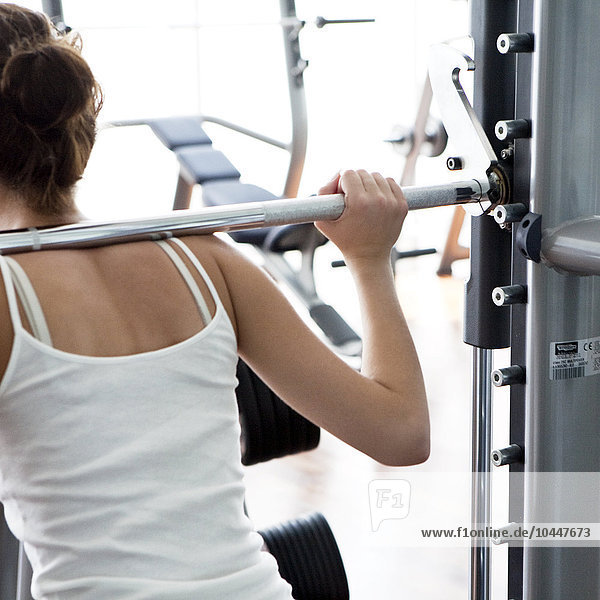 young woman lifting dumbell at gym