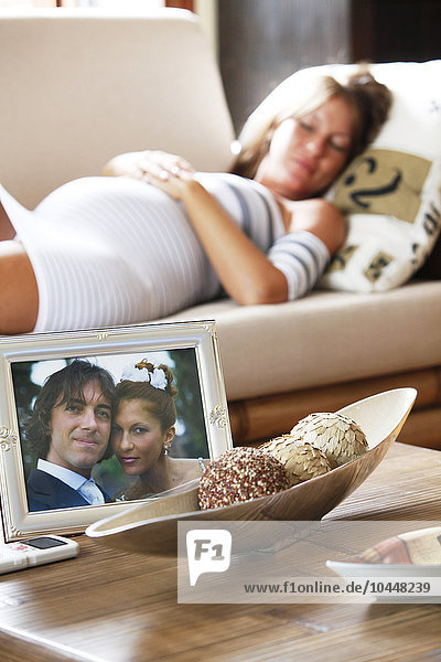 pregnant woman laying down with wedding picture on the table