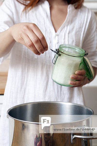 a woman who puts salt in the water  saucepan