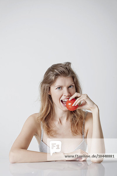 woman while biting a tomato