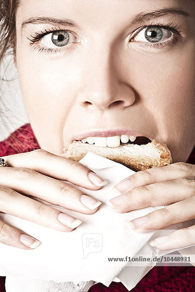 Frau isst einen Toast im Büro