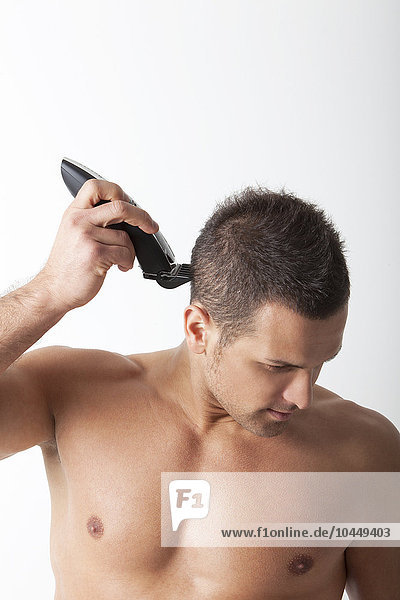 Mann rasiert die Haare mit elektrischem Rasierapparat