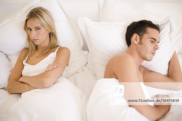 MODEL RELEASED. Relationship trouble. Couple in bed facing away from each other. Relationship trouble