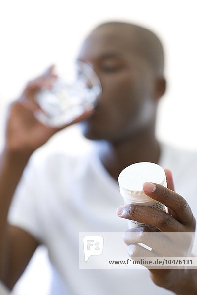 MODELL FREIGEGEBEN. Mann  der Schmerzmittel mit einem Glas Wasser einnimmt Mann  der Schmerztabletten einnimmt