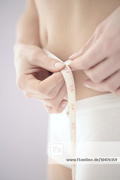 MODELL FREIGEGEBEN. Taille messen. Fünfundzwanzigjährige Frau misst ihre Taille Taille messen