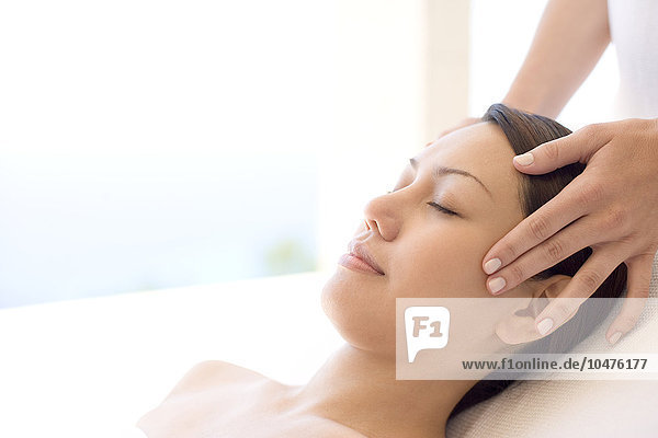 MODELL FREIGEGEBEN. Massage. Frau  die eine Schläfenmassage erhält. Eine Massage kann Muskelschmerzen oder Steifheit lindern  indem sie die Durchblutung des betroffenen Bereichs anregt. Die Massage ist eine wirksame Form des Stressabbaus und der Entspannung. Massage