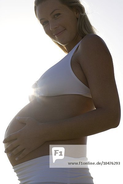 MODELL FREIGEGEBEN. Schwangere Frau fühlt ihren geschwollenen Bauch Schwangere Frau