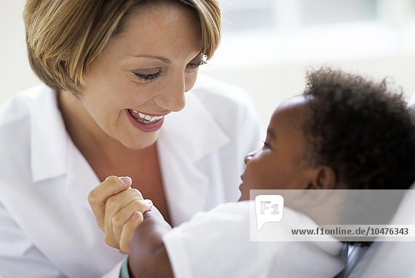 MODELL FREIGEGEBEN. Pädiatrische Untersuchung. Ärztin spielt während einer Untersuchung mit ihrem 5 Monate alten männlichen Patienten Pädiatrische Untersuchung