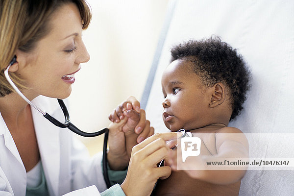 MODEL RELEASED. Paediatric examination. Doctor listening to the chest sounds of a 5-month-old male patient using a stethoscope. The stethoscope amplifies internal sounds  so that air flow to the lungs and the rhythm of the heart can be monitored. Paediatric examination
