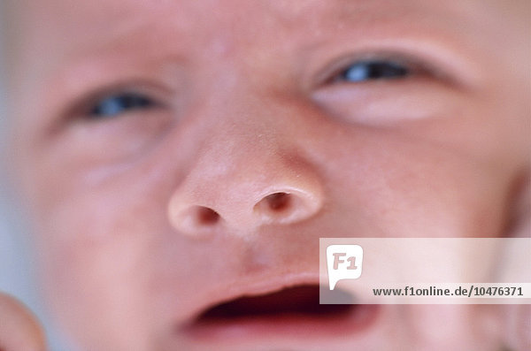 MODELL FREIGEGEBEN. Weinender kleiner Junge. Gesicht eines weinenden 2 Monate alten Babys. Das Weinen junger Babys ist ein Reflex  um auf Bedürfnisse wie Hunger oder Kälte aufmerksam zu machen. Weinender Babyjunge