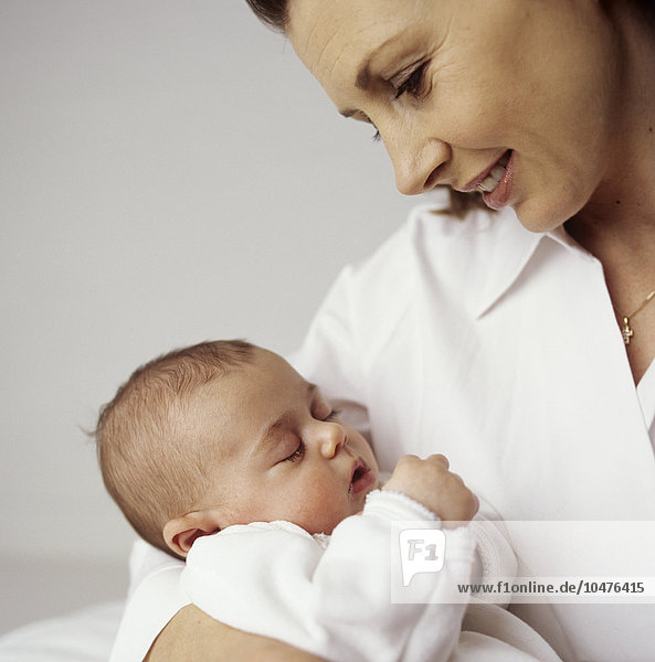 MODEL RELEASED. Mother and baby girl. 12-week-old baby girl asleep in her mother's arms. Mother and baby girl