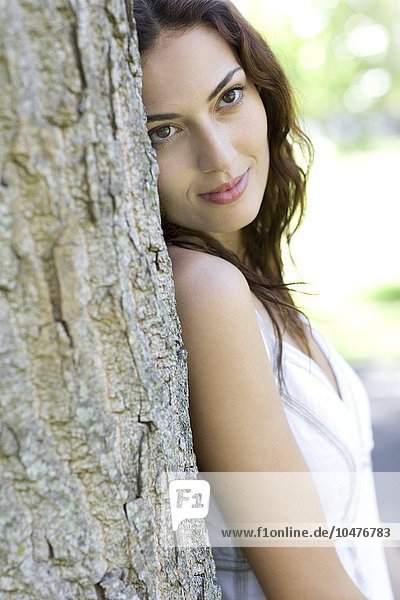 MODEL RELEASED. Woman leaning against a tree. Woman leaning against a tree