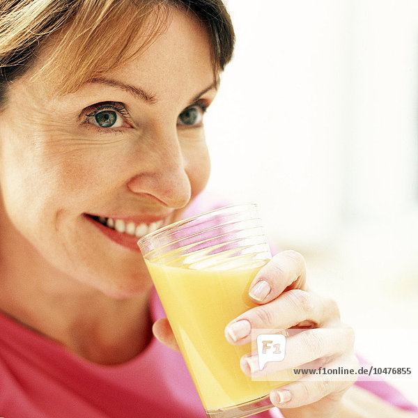 MODELL FREIGEGEBEN. Trinken von Orangensaft. Frau mit einem Glas Orangensaft in der Hand. Orangensaft ist ein gesundes Getränk  das eine gute Quelle für Vitamin C ist.