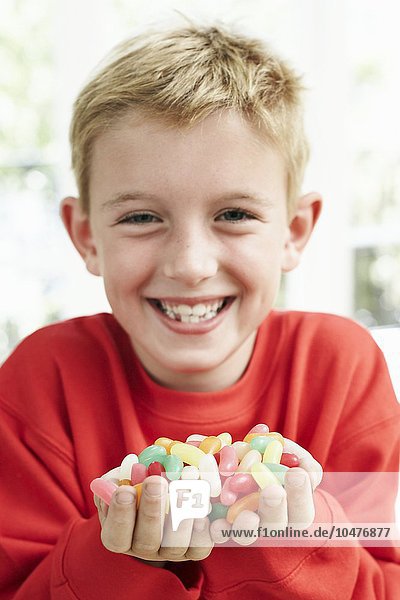 MODELL FREIGEGEBEN. Junge hält Bonbons. Er ist sechs Jahre alt. Junge hält Süßigkeiten