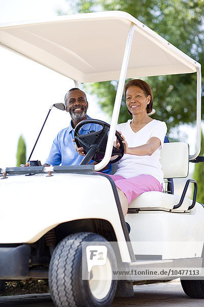 MODELL FREIGEGEBEN. Golfspieler. Mann und Frau benutzen einen Golfwagen während einer Golfrunde Golfspieler