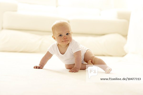 Baby sitzt auf einem Teppich