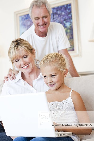 MODELL FREIGEGEBEN. Großeltern und Enkelin benutzen einen Laptop Großeltern und Enkelin