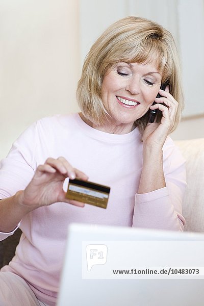 MODELL FREIGEGEBEN. Kauf mit Kreditkarte. Ältere Frau  die eine Kreditkarte benutzt  um einen Kauf über das Telefon zu tätigen Kauf mit Kreditkarte
