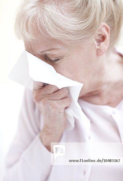 PROPERTY RELEASED. MODEL RELEASED. Senior woman blowing her nose. Senior woman blowing her nose