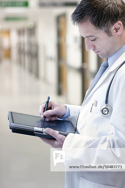 MODELL FREIGEGEBEN. Arzt  der einen Tablet-PC benutzt Arzt  der einen Tablet-PC benutzt