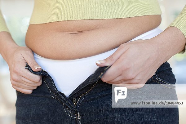 MODELL FREIGEGEBEN. Übergewichtige Frau  die darum kämpft  ihre Jeans hochzukrempeln Übergewichtige Frau