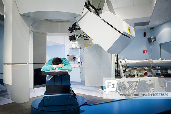 Reportage im Nationalen Onkologie-Partikel-Therapiezentrum in Mailand  Italien (Das CNAO - Centro Nazionale di Adroterapia Oncologica). Partikeltherapie ist eine hochmoderne Technik zur Behandlung von Krebs. Es besteht aus der Verwendung von Hadronen  Protonen (Protonentherapie) und Cabon-Ionen (Kohlenstoff-Ionen-Behandlung)  um Tumore zu bestrahlen. Es hat zwei therapeutische Zwecke  eine hohe ballistische Genauigkeit  die es ermöglicht  dass gesundes Gewebe um den Tumor herum verschont wird  und eine größere Effizienz bei der Behandlung bestimmter Krebsarten. Die CNAO ist das einzige Zentrum für die Carbon-Ionen-Behandlungstechnik in Europa. Ein Röntgenbild wird durchgeführt  um zu überprüfen  ob der Patient genau in der richtigen Position ist.