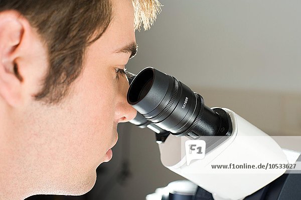 Ein Wissenschaftler  der sich ein Mikroskop ansieht.