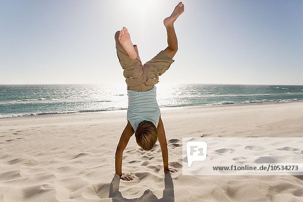 Boy doing handstand on beach