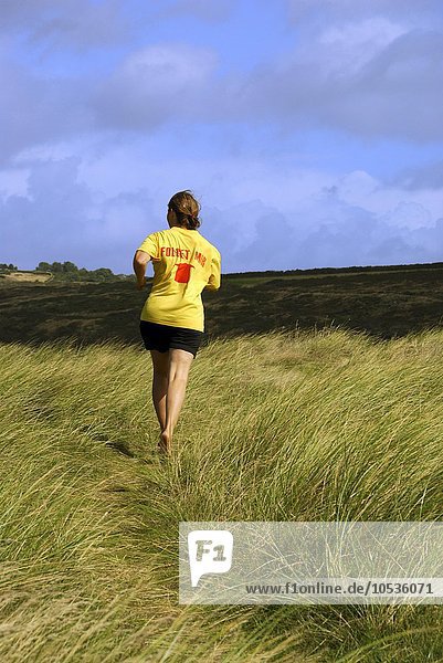 'Frau mit gelbem T-Shirt ''FOLGET MIR'' rennt auf der DÃ¼ne  Bretagne  Frankreich  Europa'