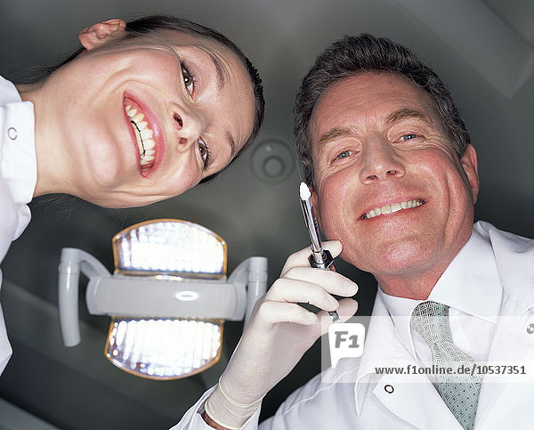 Niedriger Blickwinkel von lächelndem Zahnarzt und Assistentin