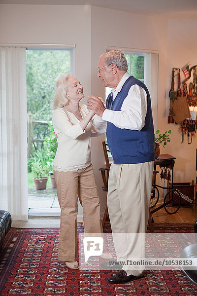 Seniorenpaar tanzt zusammen im Wohnzimmer
