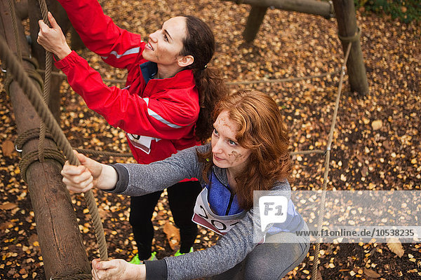 Junge Frauen klettern Seil auf assualt Kurs