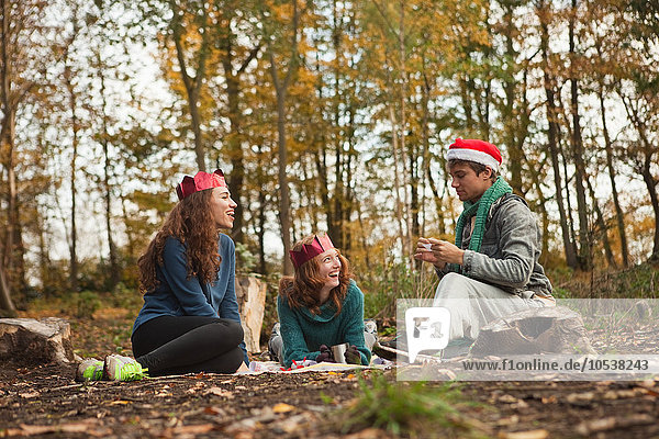Young friends in forest wearing Santa hats and crowns