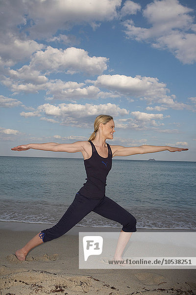 Mittlere erwachsene Frau in Yoga-Pose am Strand