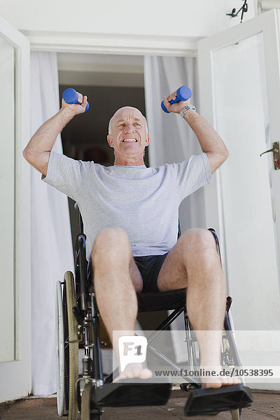 Älterer Mann im Rollstuhl beim Heben von Gewichten