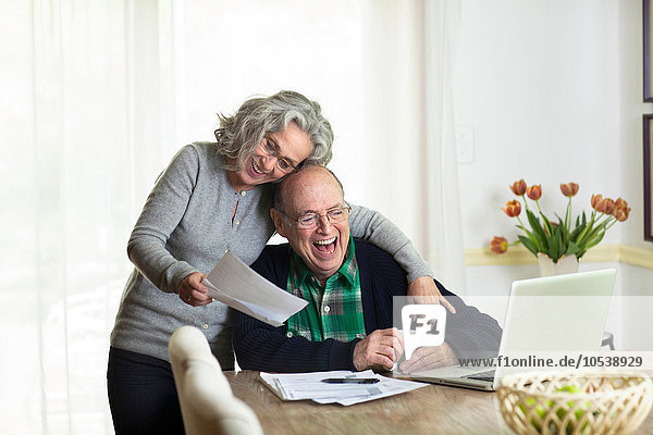 Senior couple using laptop at home  laughing