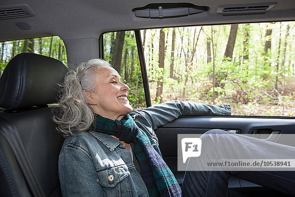 Seniorin entspannt auf dem Rücksitz des Autos