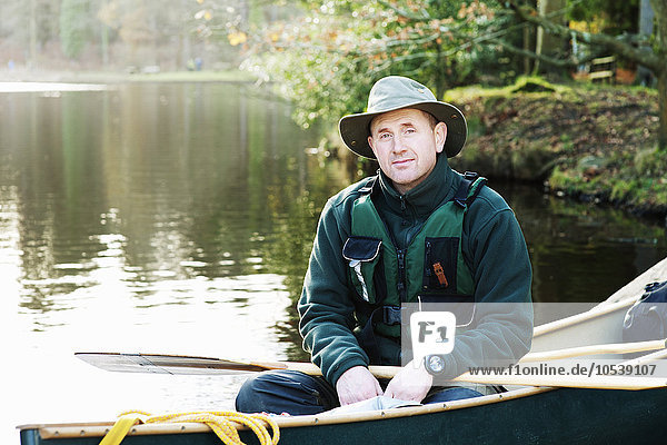 Man sitting in canoe on still lake