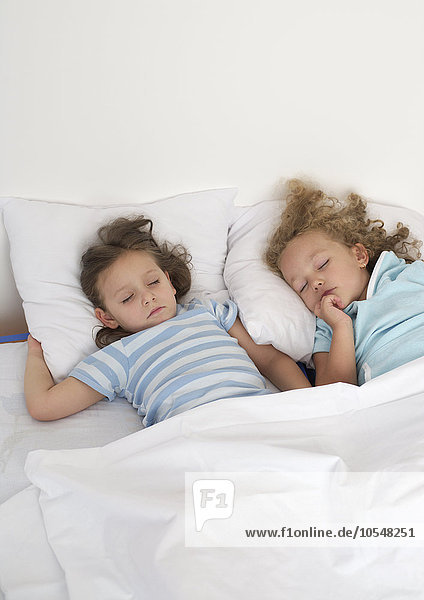 Zwei Mädchen liegen schlafend in einem Bett