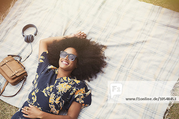 Draufsicht lächelnde Frau mit Afro auf Decke im Freien liegend