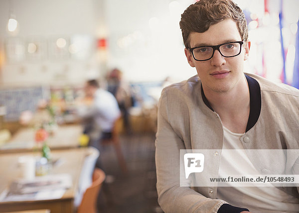 Portrait confident man with eyeglasses in cafe