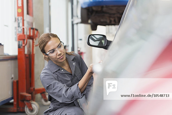 Female mechanic examining car in auto repair shop