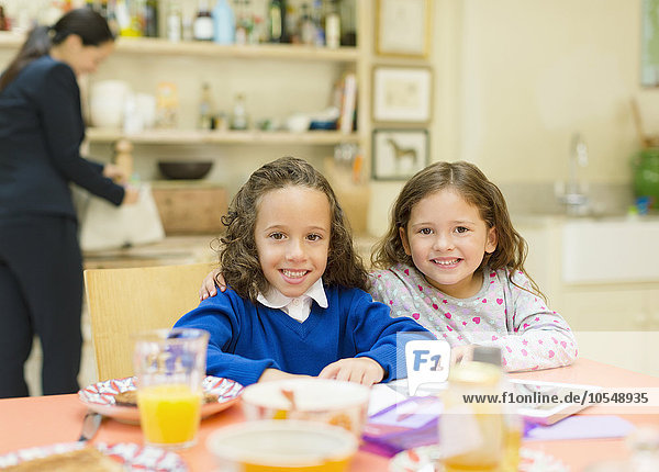Portrait lächelnde Schwestern am Frühstückstisch