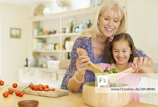 Großmutter und Enkelin beim Salatwerfen in der Küche