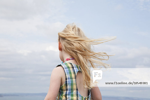 Ein Mädchen  dessen Haare im Wind wehen.