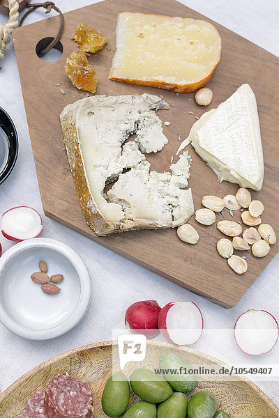 Hochwinkelansicht einer Käseplatte  Käse  Oliven  Nüsse und Radieschen auf einem Tisch.